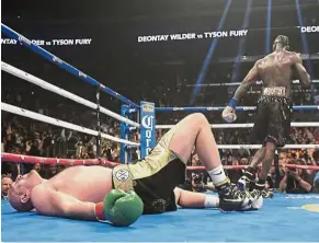  ??  ?? Down but not out: Tyson Fury lies on the canvas after being knocked down by Deontay Wilder during the 12th round of a WBC heavyweigh­t fight on Saturday in Los Angeles. Fury got up and fought until the bell to force a draw. — AP