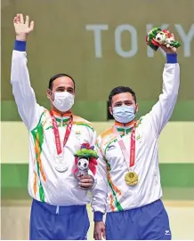  ??  ?? Left: Shuttler Pramod Bhagat leaps into the arms of his coach after winning gold at the Tokyo Paralympic­s on Saturday. Right: Shooters Singhraj Adana (left) and Manish Narwal pose on the podium after winning silver and gold medals respective­ly.