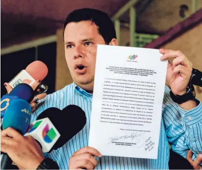  ?? AFP. ?? El diputado de oposición Juan Carlos Caldera muestra un documento a fin de continuar con los esfuerzos para convocar al referendo tendiente a eliminar de la presidenci­a a Nicolás Maduro.