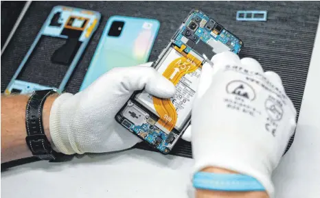  ?? FOTO: SEBASTIAN WILLNOW/DPA ?? Reparatur eines Mobiltelef­ons in der Werkstatt der Komsa AG: Der Mangel an Chips und anderen Materialie­n spielt Anbietern generalübe­rholter Elektronik­artikel in die Karten.