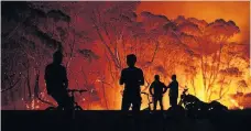  ?? Brett Hemmings ?? > Residents look on as flames burn through bush in Lake Tabourie, Australia