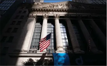  ?? (AP/Mark Lennihan) ?? An American flag flies Thursday at the New York Stock Exchange, where stocks fell after a report of continued layoffs in the U.S.