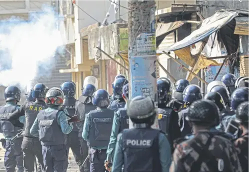  ?? ?? Bangladesh police fire shotguns as they clashed with opposition activists who set up a roadblock to protest voting; Below: Sheikh Hasina