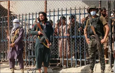  ?? (AP/Muhammad Sajjad) ?? Taliban fighters and a Pakistani paramilita­ry soldier (right) stand guard Saturday on their respective sides at a border crossing at Torkham in Pakistan’s Khyber district. Pedestrian movement is being limited at the crossing, with only stranded people on both sides and trucks taking goods to Afghanista­n being allowed through.