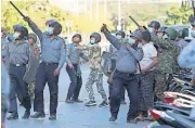  ??  ?? A policeman aims a slingshot toward an unknown target Monday during a crackdown on anti-coup protesters holding a rally in front of the Myanmar Economic Bank in Mandalay, Myanmar. [THE ASSOCIATED PRESS]