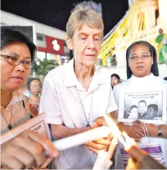  ?? — AFP photo ?? File photo shows Fox (centre) lighting a candle as she attends a prayer vigil for slain Catholic priests in front of Quiapo church in Manila.