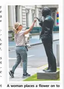  ??  ?? A woman places a flower on to the statue of former Victorian premier John Cain.