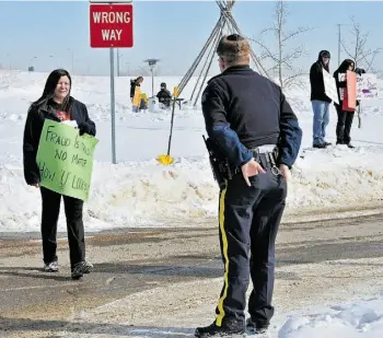  ?? EDMONTON JOURNAL/FILE ?? A policeman talks to a protester in March 2011 when a group of parents and students from the Enoch First Nations Reserve raised concerns about allegation­s of fraud at Kitaskinaw School. Charges laid against two school administra­tors have now been stayed.