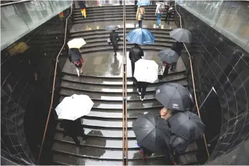  ?? — Reuters photo ?? Office workers are seen during wet weather in Sydney, Australia.