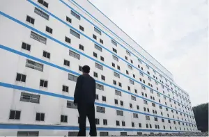  ?? PHOTO: REUTERS ?? A new horizon . . . A worker gazes at a sevenstore­y pig building of Guangxi Yangxiang’s farm at Yaji Mountain Forest Park in Guangxi province, China.