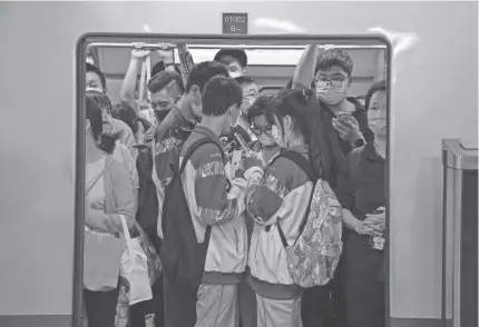  ?? ANDY WONG/AP ?? Students browse their smartphone­s Sept. 14 inside a subway train in Beijing. China has set new rules limiting the amount of time kids can spend playing online games.