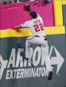  ?? JOHN BAZEMORE — THE ASSOCIATED PRESS ?? Washington right fielder Juan Soto climbs the wall as he chases a ball hit for a three-run home run by Atlanta’s Dansby Swanson during the seventh inning Friday in Atlanta.