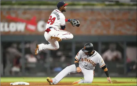  ?? AP PHOTO/JOHN AMIS ?? Atlanta Braves second baseman Adeiny Hechavarri­a (24) throws above San Francisco Giants’ Cristhian Adames after forcing him out at second base for a double play on Mauricio Dubon at first base during the fifth inning of a baseball game, on Saturday, in Atlanta.