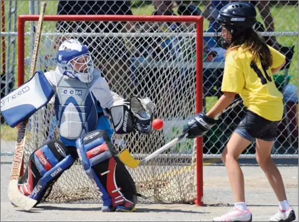  ?? CLIFFORD SKARSTEDT Examiner ?? Team Optomist forward Kyla Thompson and goalie Zach Anderson eye a loose ball in a ball hockey tournament during Family Fun Day at the 46th annual Shamrock Festival in Ennismore. See more photos on Page D1.