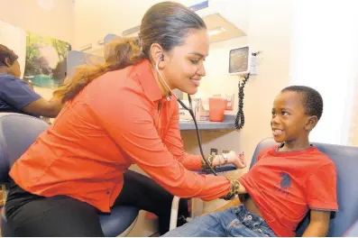  ??  ?? Dr Jhenelle Hew listens to the heartbeat of Romeiro Grant during Member of Parliament Julian Robinson’s backto-school health and dental fair at the UTech School of Dentistry, St Andrew, last Saturday. Scores of persons turned out to take advantage of the all-day event that catered mostly to children.