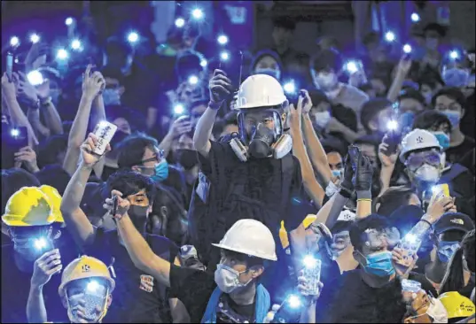  ?? Vincent Yu The Associated Press ?? Protesters shine lights from their cellphones Friday outside police headquarte­rs in Hong Kong.