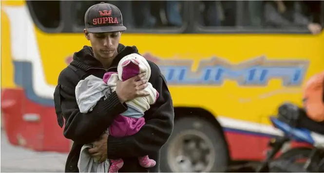  ?? Raul Arboleda/AFP ?? Venezuelan­o carrega bebê em um acampament­o improvisad­o perto de um terminal de ônibus em Bogotá; mais de cem migrantes dormem de forma precária no local