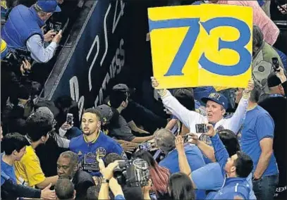 ?? JEFF CHIU / AP ?? Un aficionado sostiene el número 73 (la cifra de triunfos de los Warriors) cerca de Stephen Curry