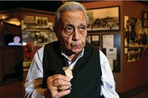  ?? MIGUEL MARTINEZ/MIGUEL.MARTINEZJI­MENEZ@AJC.COM ?? Holocaust survivor George Rishfeld displays the St. Christophe­r medal his Catholic rescuers gave him while they hid him in Warsaw, Poland. Rishfeld did not begin talking publicly about his experience­s until 1994.