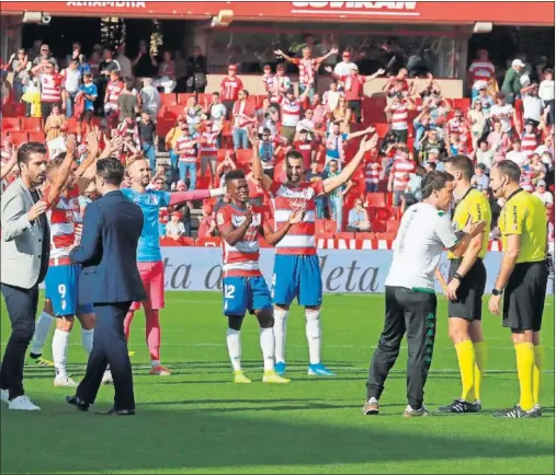  ??  ?? La plantilla del Granada celebra la victoria con sus aficionado­s mientras Rubi le explica alguna acción del partido a Mateu Lahoz.