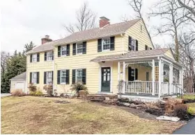  ??  ?? Yellow siding with black shutters and a white-trimmed side porch with fretwork trim lend curbside appeal to the house.