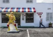  ?? DAMON HIGGINS / THE PALM BEACH POST ?? Alex Seeley, who owned Nothin’ Fancy barbershop in Lake Worth, walks past the Hulk Hogan statue he set up outside before entering for work in 2013.