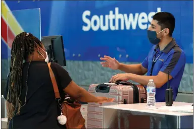  ?? (AP) ?? A Southwest Airlines employee helps a passenger last month at the ticket counter at Love Field in Dallas.