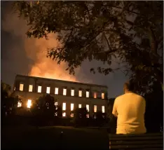  ?? AP PHOTO/LEO CORREA ?? A man watches as flames engulf the 200-year-old National Museum of Brazil, in Rio de Janeiro, on Sunday.