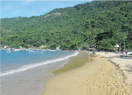  ?? THE ASSOCIATED PRESS ?? Tourists walk along the beach in the village of Vilo do Abraao in Ilha Grande, three hours by boat from Rio de Janeiro. The tropical island’s colourful past includes being a pirate refuge.