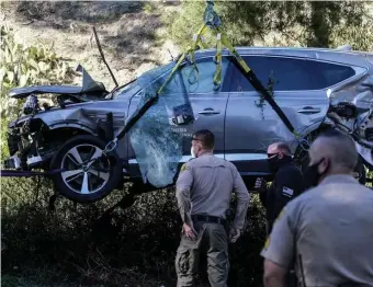  ?? AP FILE PHOTOS ?? LUCKY TO BE ALIVE: Law enforcemen­t officers watch as a crane is used to lift a vehicle following a rollover accident involving golfer Tiger Woods on Tuesday in the Rancho Palos Verdes section of Los Angeles. Woods suffered severe injuries to his leg and underwent surgery. At left, Woods reacts after winning the Masters on April 14, 2019.