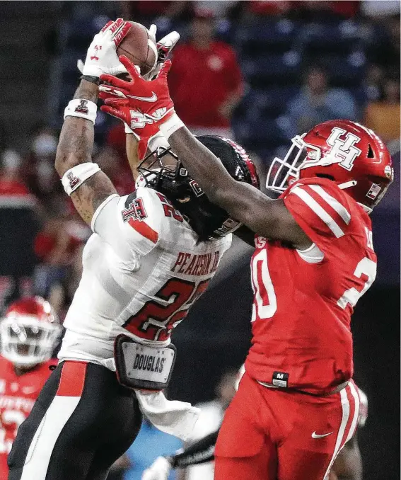  ?? Karen Warren / Staff photograph­er ?? Reggie Pearson intercepts a pass — one of four picks Texas Tech made during the game — in front of UH’s KeSean Carter on Saturday at NRG Stadium.