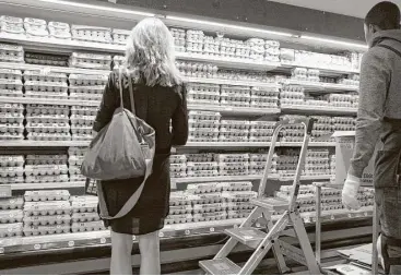  ?? Mark Lennihan / Assocaited Press ?? A shopper looks over the egg selection at a New York Whole Foods market. Organic eggs were among the items that cost less at Whole Foods locations as Amazon took over on Monday.