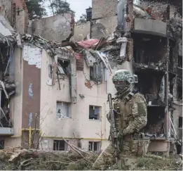  ?? (Gleb Garanich/Reuters) ?? A UKRAINIAN serviceman is seen yesterday near buildings destroyed by Russian shelling in the town of Irpin, outside of Kyiv.