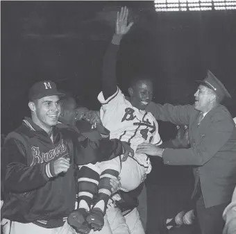  ?? Associated Press file ?? Milwaukee Braves’ Hank Aaron is carried from the field by teammates after they won the National League pennant with a 4-2 victory against the St. Louis Cardinals on Sept. 23, 1957.