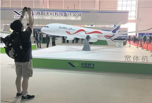  ?? REUTERS ?? A man takes picture of the model of a widebody jet, which is planned to be developed by Commercial Aircraft Corporatio­n of China (COMAC) and Russia’s United Aircraft Corporatio­n (UAC) at an air show in Zhuhai, China yesterday.