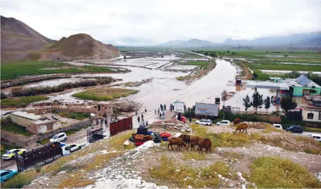  ?? Agence France-presse ?? ↑ People gather near a flooded area following a flash flood in Feroz Nakhchir district of Samangan Province on Saturday.