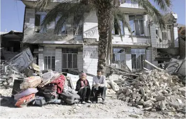  ?? PICTURE: AP ?? A couple sits yesterday in front of a house destroyed in the earthquake in Sarpol-e-Zahab in western Iran. The authoritie­s have called off rescue operations, saying the chances of finding anyone alive after Sunday’s deadly earthquake in the border region of Iran and Iraq were remote.