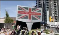  ??  ?? People sit under a billboard in Manchester city centre, Tuesday May 23, 2017, the day after the suicide attack at an Ariana Grande concert that left 22people dead as it ended on Monday night.