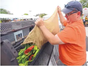  ?? ADOLPHE PIERRE-LOUIS/JOURNAL ?? Stan Higgins pours a bag of Hatch green chiles into a roster during the 20th Annual Chile Festival held at Shepherd of the Valley Presbyteri­an Church in August 2017.