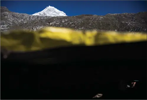  ?? Jabin Botsford/The Washington Post ?? Victor Morales, the solitary watchman whose job is to call the city of Huaraz to warn of potential floods, waits for breakfast in his stone hut near Lake Palcacocha, a swollen glacial lake in the Andes mountain range.