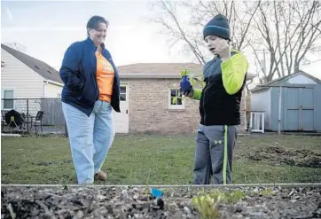  ?? ERIN HOOLEY/CHICAGO TRIBUNE PHOTOS ?? Lonna Drobi and her 9-year-old son, Omar, check out their raised garden bed at their home on Tuesday in Waukegan. Drobi has made some lifestyle changes, including a backyard garden and composting.