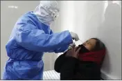  ??  ?? A doctor takes a swab from a woman to test for the COVID-19virus at a fever clinic in Yinan county in eastern China’s Shandong province on Wednesday. China on Wednesday reported another drop in the number of new cases of a viral infection and 97 more deaths, pushing the total dead past 1,100.