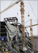  ?? GERALD HERBERT — THE ASSOCIATED PRESS ?? Workers in a bucket hoisted by a crane begin the process of preparing the two unstable cranes for implosion at the collapse site of the Hard Rock Hotel.