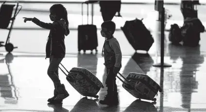  ?? Rick Bowmer / Associated Press ?? Young travelers pass through Salt Lake City Internatio­nal Airport. Airlines have canceled thousands of flights since Dec. 24.