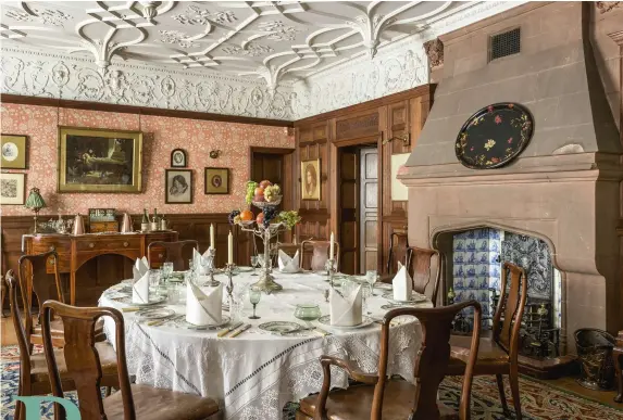  ??  ?? ABOVE A plain stone replace with a Tudor- inspired arch is inset with blue-andwhite Delft tiles. The elaborate pendant ceiling and frieze is by Shuffrey. Furniture in the Georgian style dates from the 19th and early 20th centuries, while the chairs may...