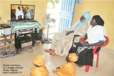  ??  ?? Family members in a village outside Abuja, Nigeria, watch satellite TV