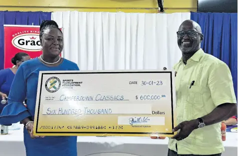  ?? PHOTO BY DANIEL WHEELER ?? Camille Allen-walters (left), chairperso­n for the Camperdown Classic organising committee, collects a sponsorshi­p cheque from Sports Developmen­t Foundation general manager Denzil Wilks during yesterday’s press launch for the event at the Camperdown High School.