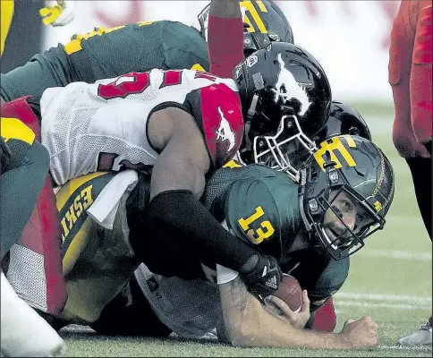  ?? GREG SOUTHAM/ POSTMEDIA ?? EDM CGY Eskimos Mike Reilly (13) is tackled by the Stampeders players in Edmonton on Saturday. Esks beat Stamps 29:20.