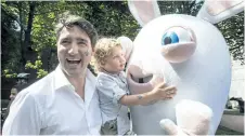  ?? PAUL CHIASSON/THE CANADIAN PRESS ?? Hadrian Trudeau hugs a rabbit while in the arms of his father, Prime Minister Justin Trudeau, at a street party for the Fete National du Quebec, Saturday.