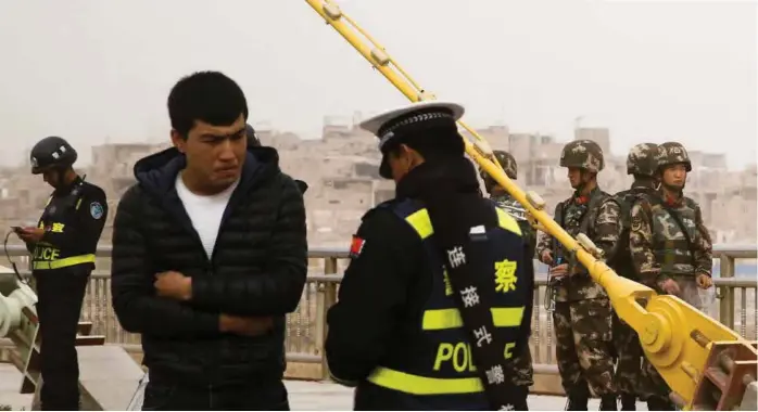  ?? FOTO: THOMAS PETER, REUTERS / NTB SCANPIX ?? En kinesisk politimann sjekker ID-kortet til en mann i Kashgar i Xinjiang-regionen i mars 2017. Så mange som ti prosent av regionens uigurer skal vaere plassert i omskolerin­gsleirer de siste årene.